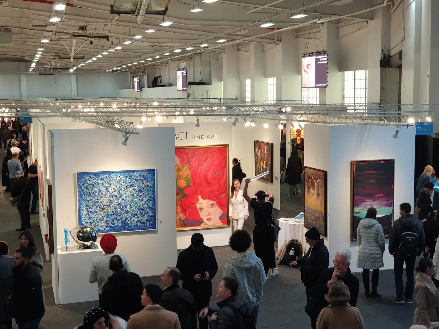 Crowds on the fair floor beside the AGI Fine Art booth at Artexpo New York, April 2024, Pier 36
