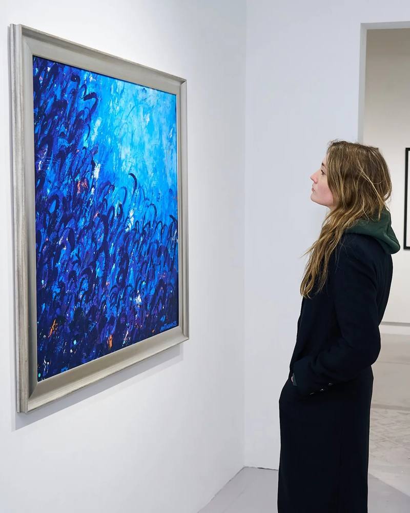 A visitor looking at a large blue painting