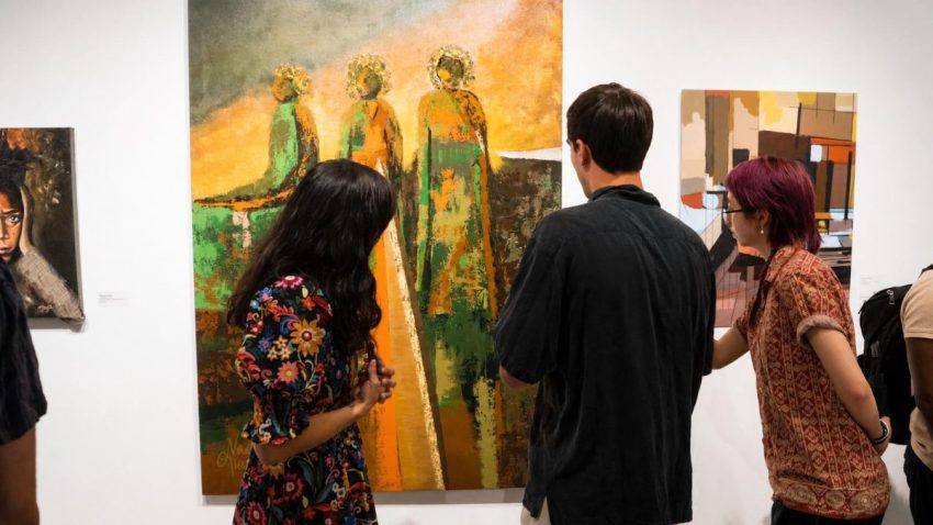 Visitors in front of a large painting of figures