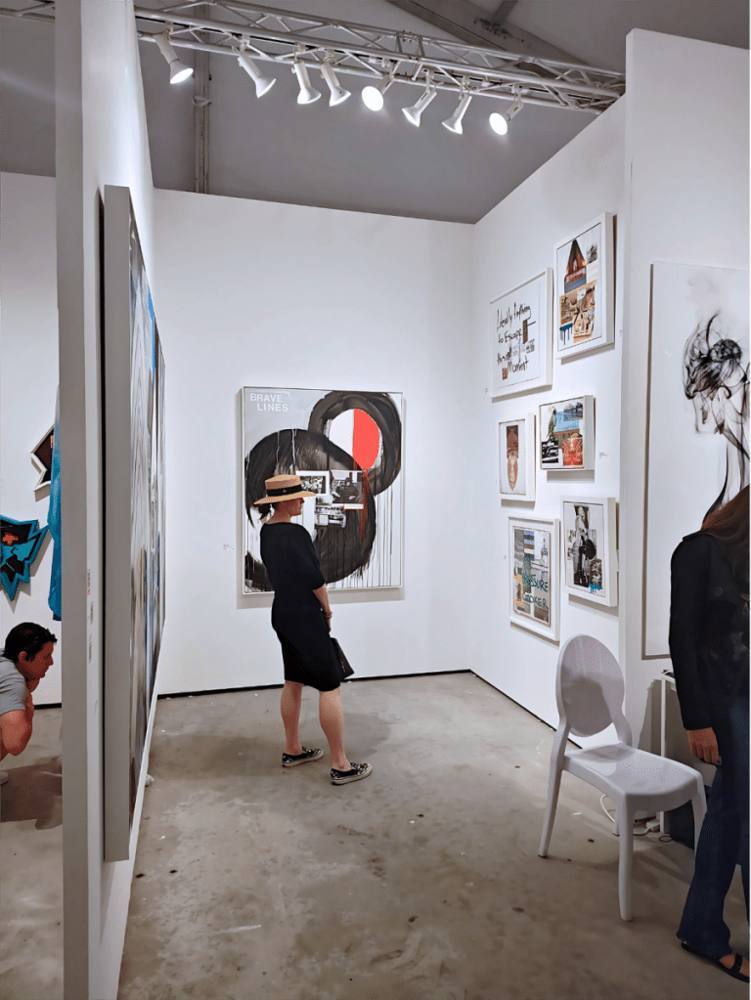 A visitor in an art fair booth hung with black and white works