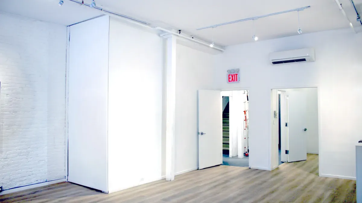 The entrance end of The Loft, with a full-height movable panel against the brick wall and the doors out to the stair landing