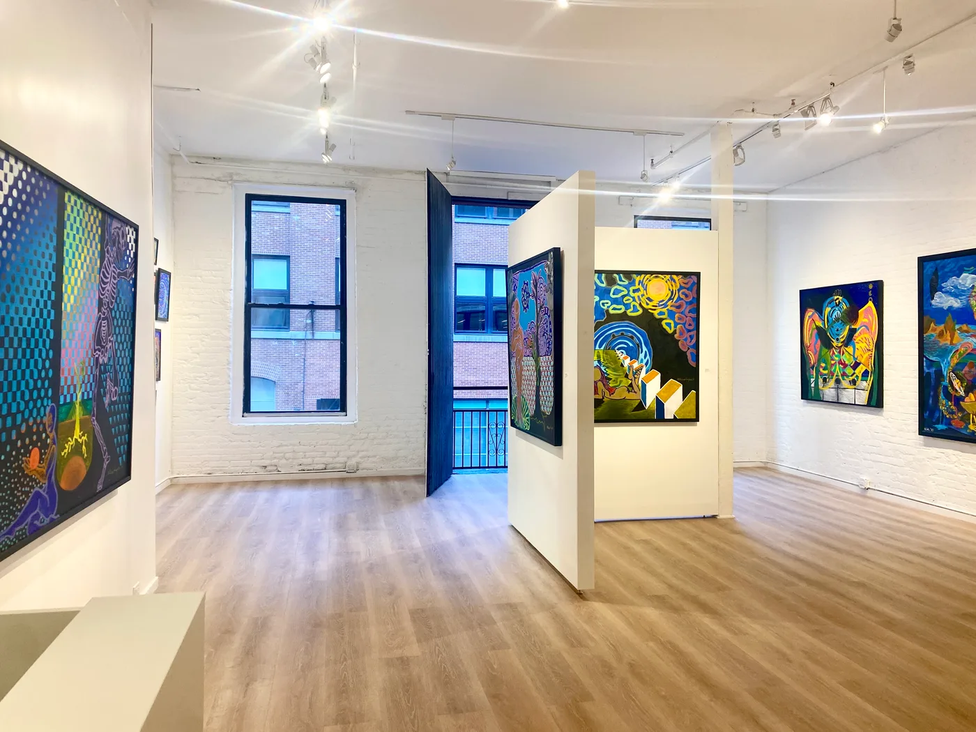Interior of The Loft at 532 West 25th Street, showing exposed white-washed brick walls, wood flooring, and an open door