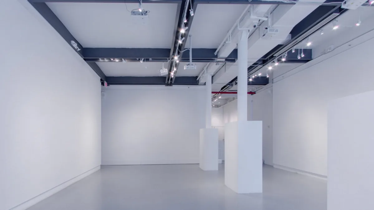 The 530 West 25th Street gallery with bare white walls and empty display plinths, lit by ceiling track lights