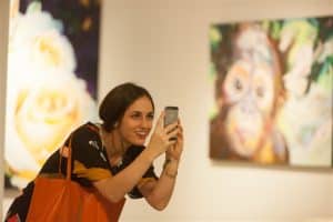 A gallery visitor taking a picture of artwork by Alana O’Hern
