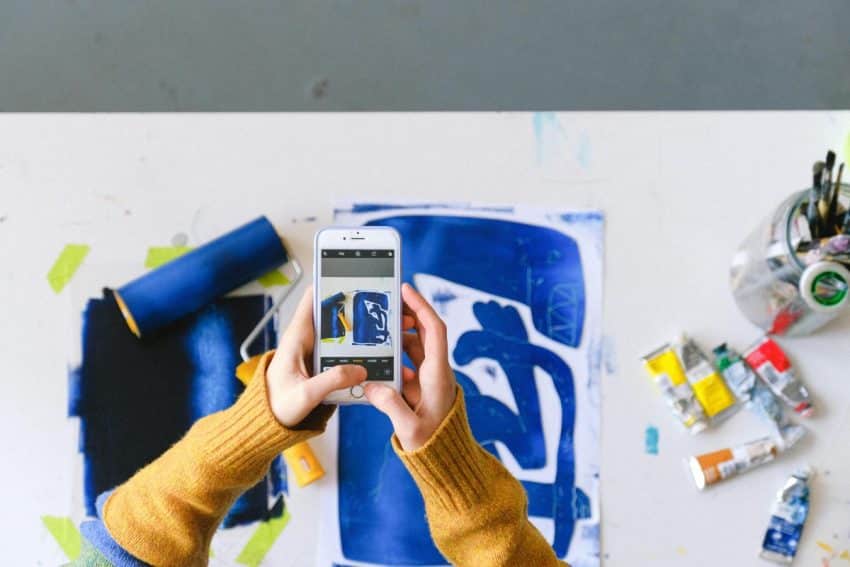 Taking a picture that teases a newly-made artwork on a smartphone is a great way to generate interest in your artist newsletter