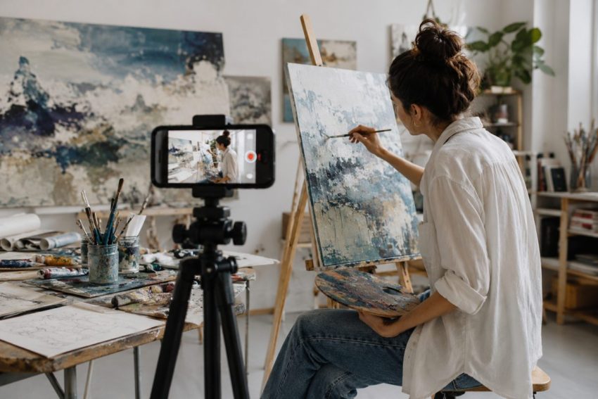 Artist recording the painting process in a studio, illustrating how process-driven content boosts visibility on Instagram and TikTok.
