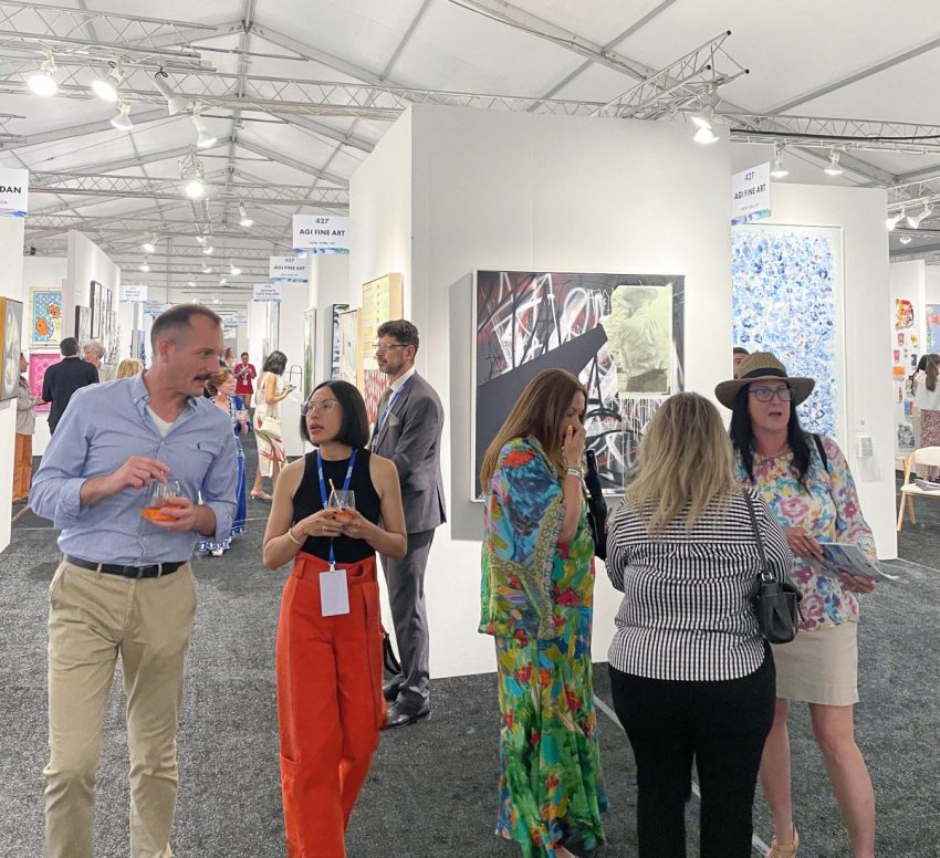 AGI Fine Art Booth 427 at the Hamptons Fine Art Fair, featuring contemporary artworks and visitors exploring the exhibition.