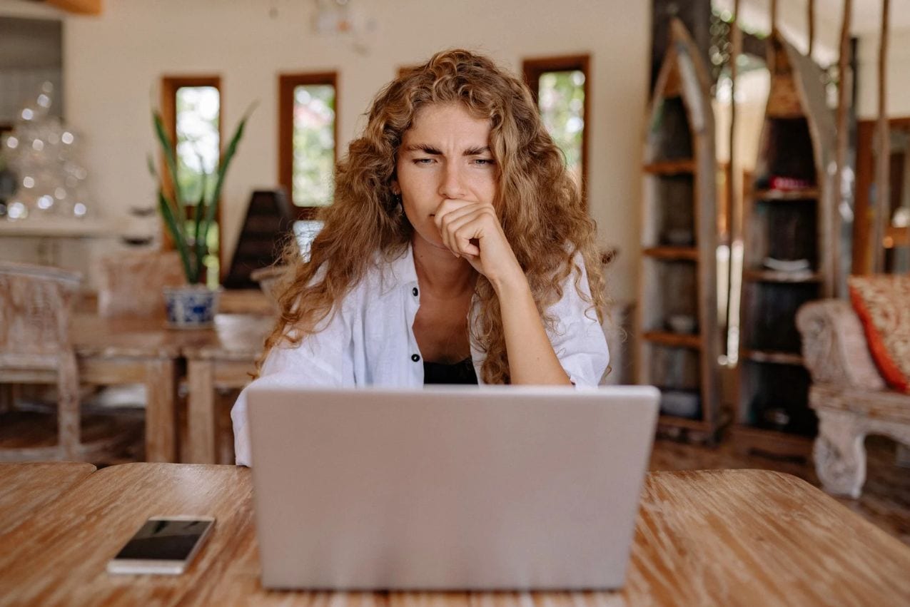 Woman thoughtfully reviewing a potential collaboration offer on her laptop, considering the value of unpaid creative work.