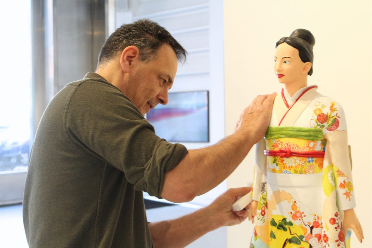 Artist Marc examining his kimono-clad figurative sculpture for any damage after it arrived by shipment at Agora Gallery