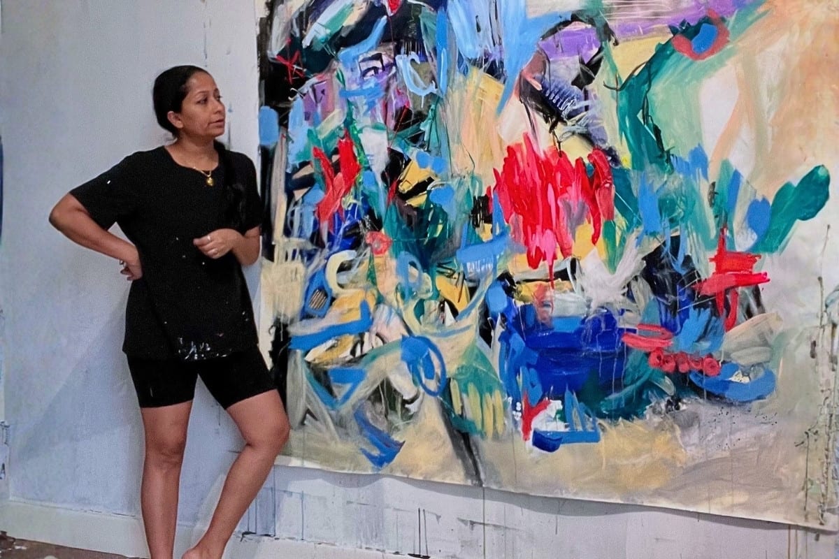 Artist Nupur Jha studies one of her large, vibrant abstract paintings in her studio.